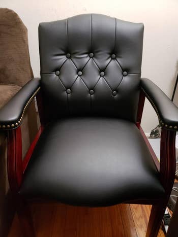 Reviewer image of black and dark wood chair on hardwood floor next to brown chair