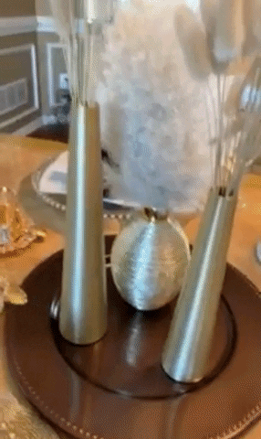 Reviewer video of two narrow gold vases on a brown plate sitting on top of a table