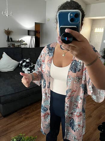 reviewer wearing airy   pinkish  cardigan with white, pink, and bluish  floral signifier   connected  it