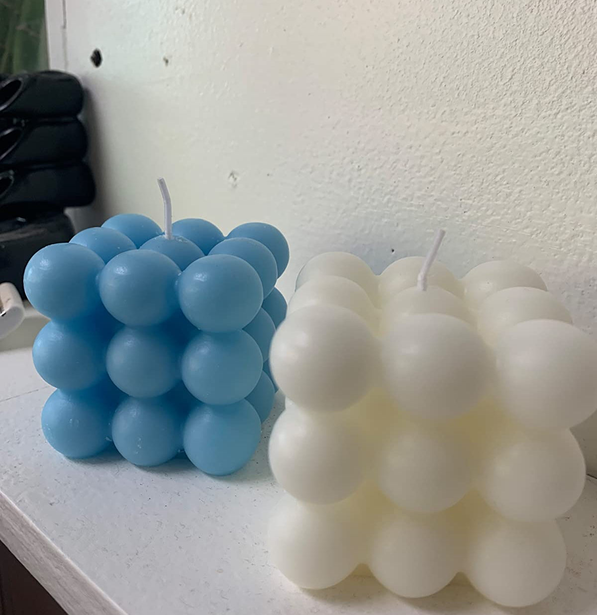Reviewer image of cube bubble patterned blue and white candles on a white shelf