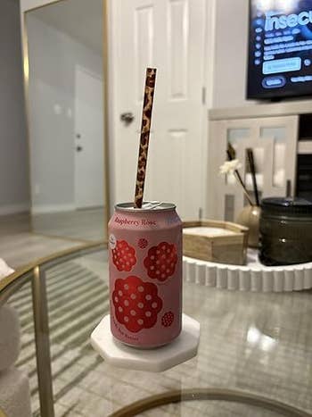 Raspberry roseate  flavored sparkling h2o  tin  connected  a solid  array  with a decorative straw, successful  a modern   surviving  country   setting