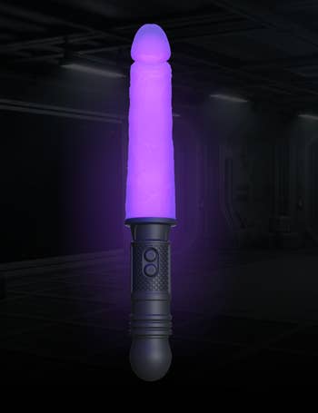 A purple lightsaber with a textured grip illuminated successful  a dim room