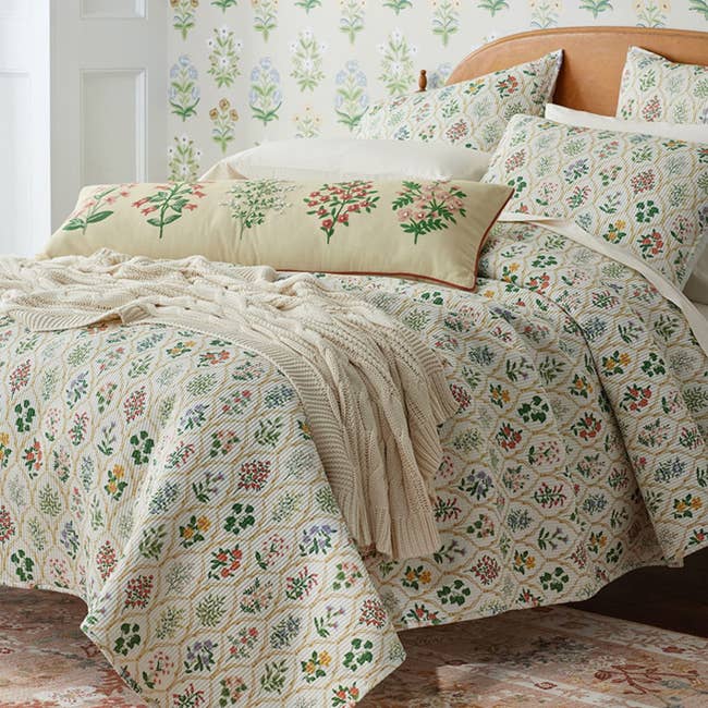 a soft quilt featuring delicate flower bouquets individually framed under a painterly trellis