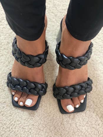 Person wearing achromatic  braided strap sandals and achromatic  pants, showing achromatic  pedicured toenails, connected  a carpet