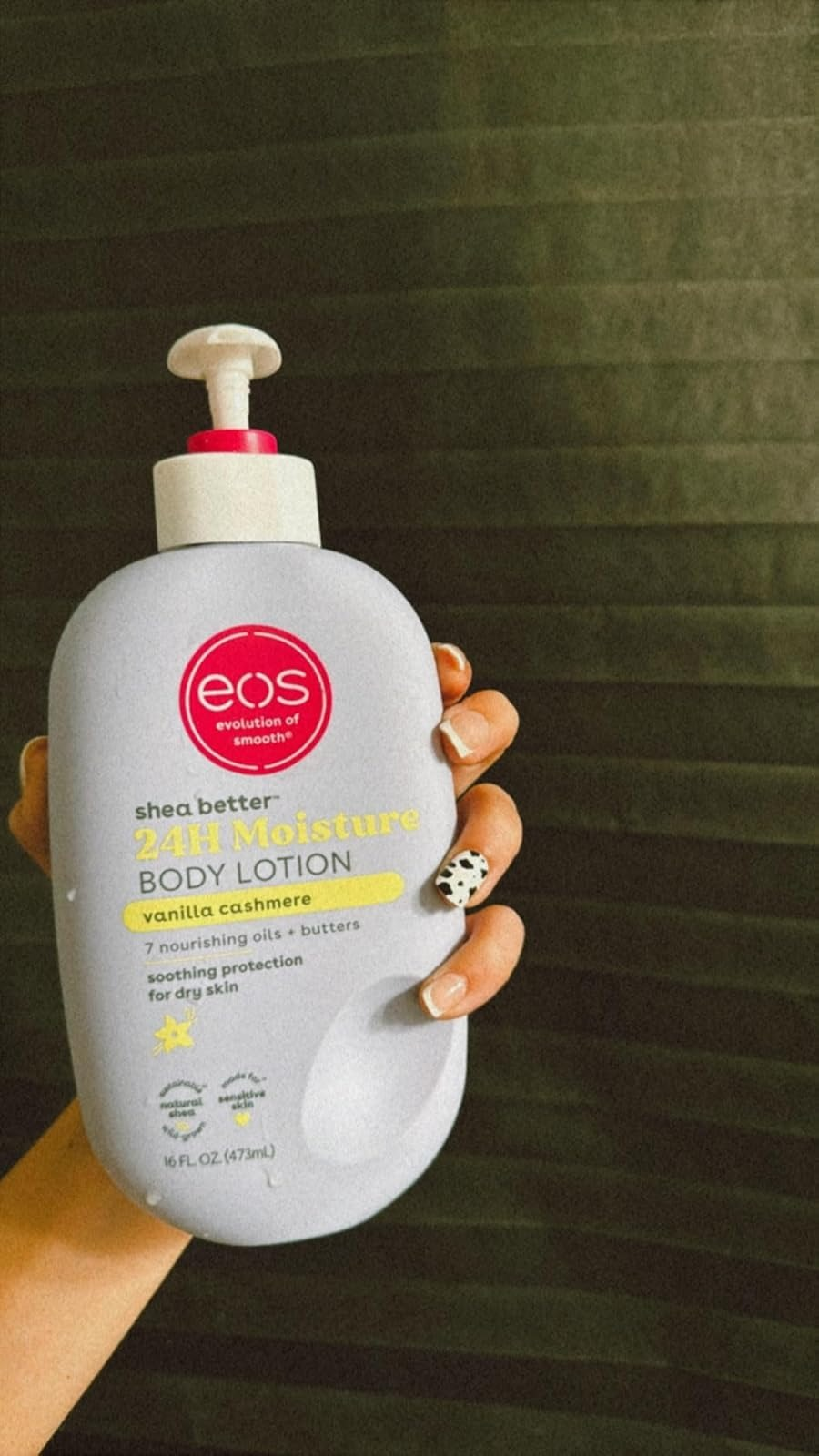 Tangan memegang EOS Shea lebih baik lotion tubuh kelembaban 24 jam di Vanilla Cashmere. Fitur Produk Terdaftar: 7 Minyak Bergizi + Butters, Menenangkan Kulit Kering