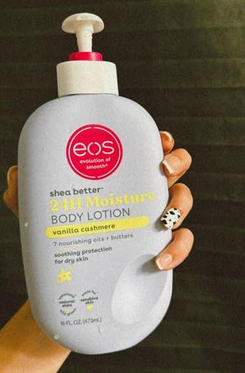 Tangan memegang EOS Shea lebih baik lotion tubuh kelembaban 24 jam di Vanilla Cashmere. Fitur Produk Terdaftar: 7 Minyak Bergizi + Butters, Menenangkan Kulit Kering