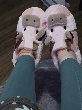 Person wearing plush pig-themed slippers, relaxing with legs stretched out, showcasing cozy and whimsical footwear