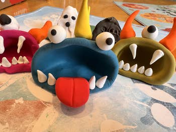 Playful, colorful clay monster figures with exaggerated facial features and horns, displayed connected  a table