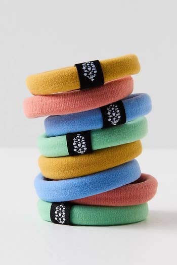 A stack of eight hair ties in green, blue, yellow, and pink 