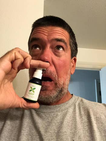Person using a nasal spray bottle labeled