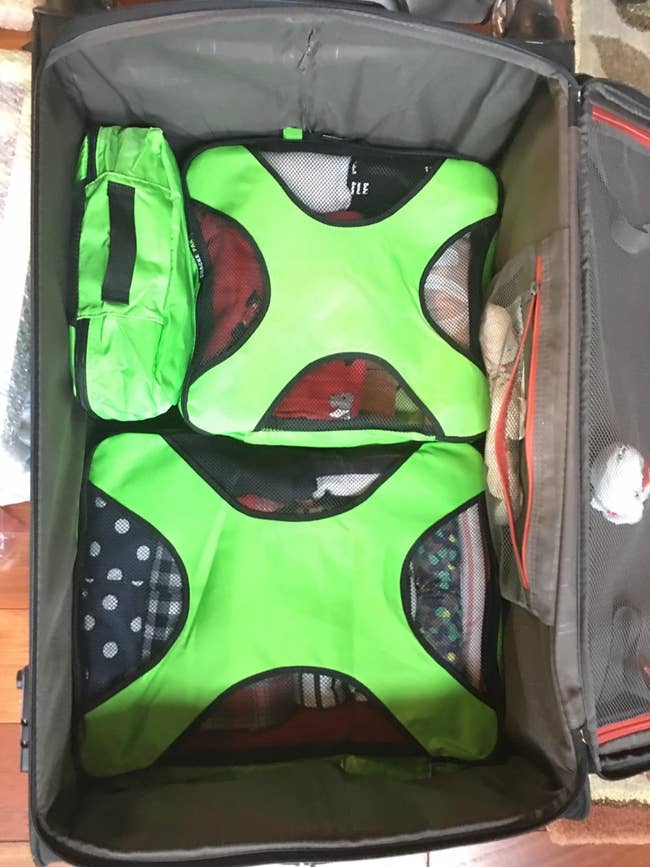 three packing cubes inside of a rolling suitcase