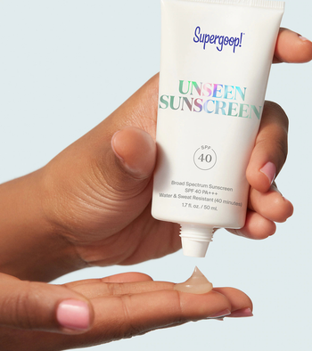 a model squeezing the clear sunscreen onto their hand 