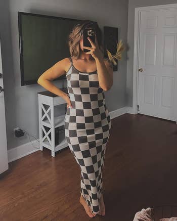 reviewer in a sleeveless checkered dress poses for a mirror selfie