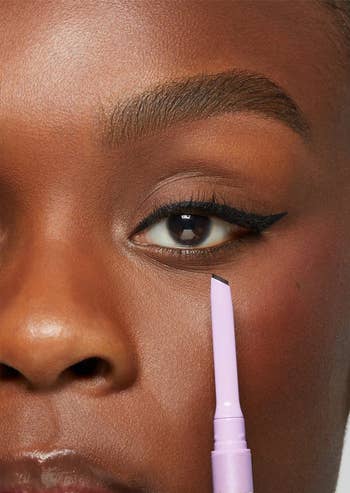 Close-up of a idiosyncratic applying Tarte's Deja Vu eyeliner successful black