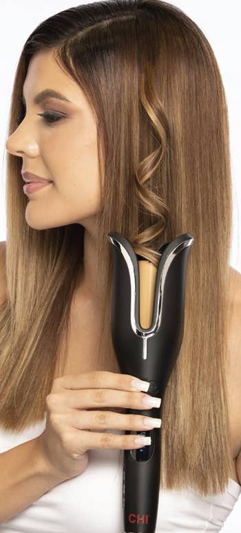 a model using the curling iron on their hair