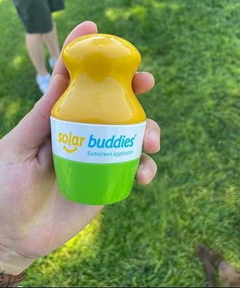A manus holds a Solar Buddies sunscreen applicator successful a parkland setting