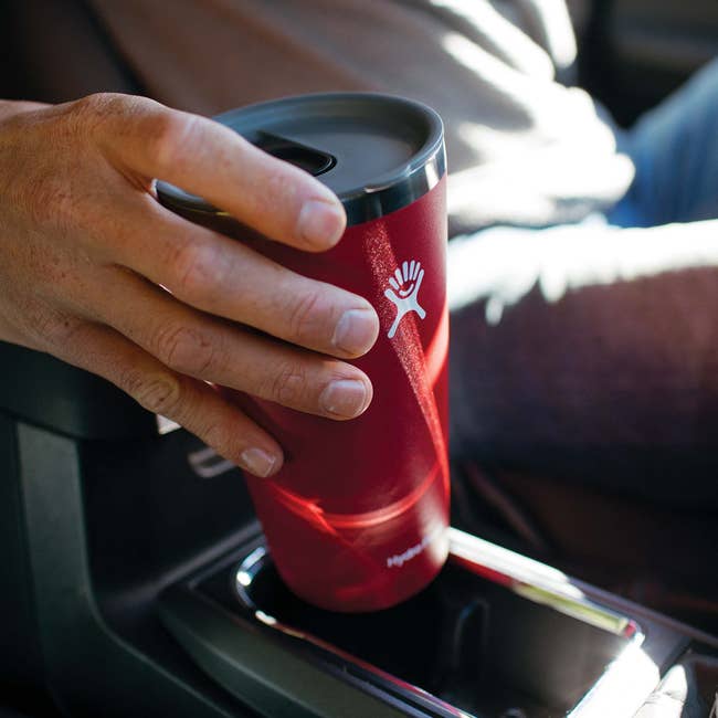 hand placing the red tumbler into a car cup holder