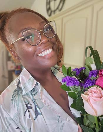 model smiling and holding a bouquet, wearing a tropical people     shirt