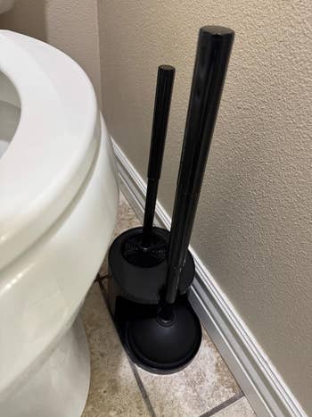 Toilet plunger and cleaning brush set in holder next to a toilet