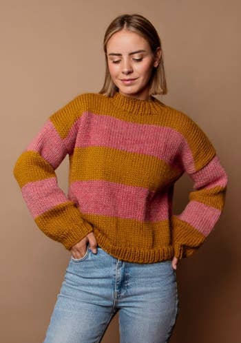 model in a striped mustard and pink sweater