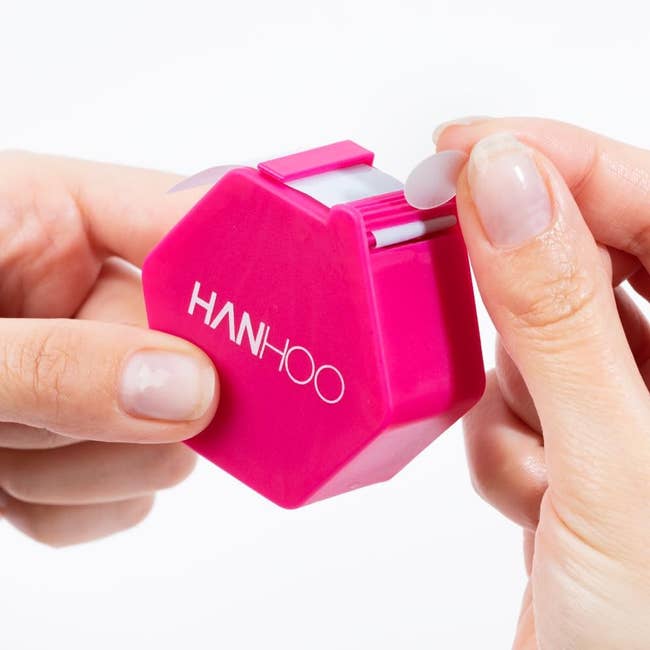 Hands holding a pink HANHOO pimple patch dispenser