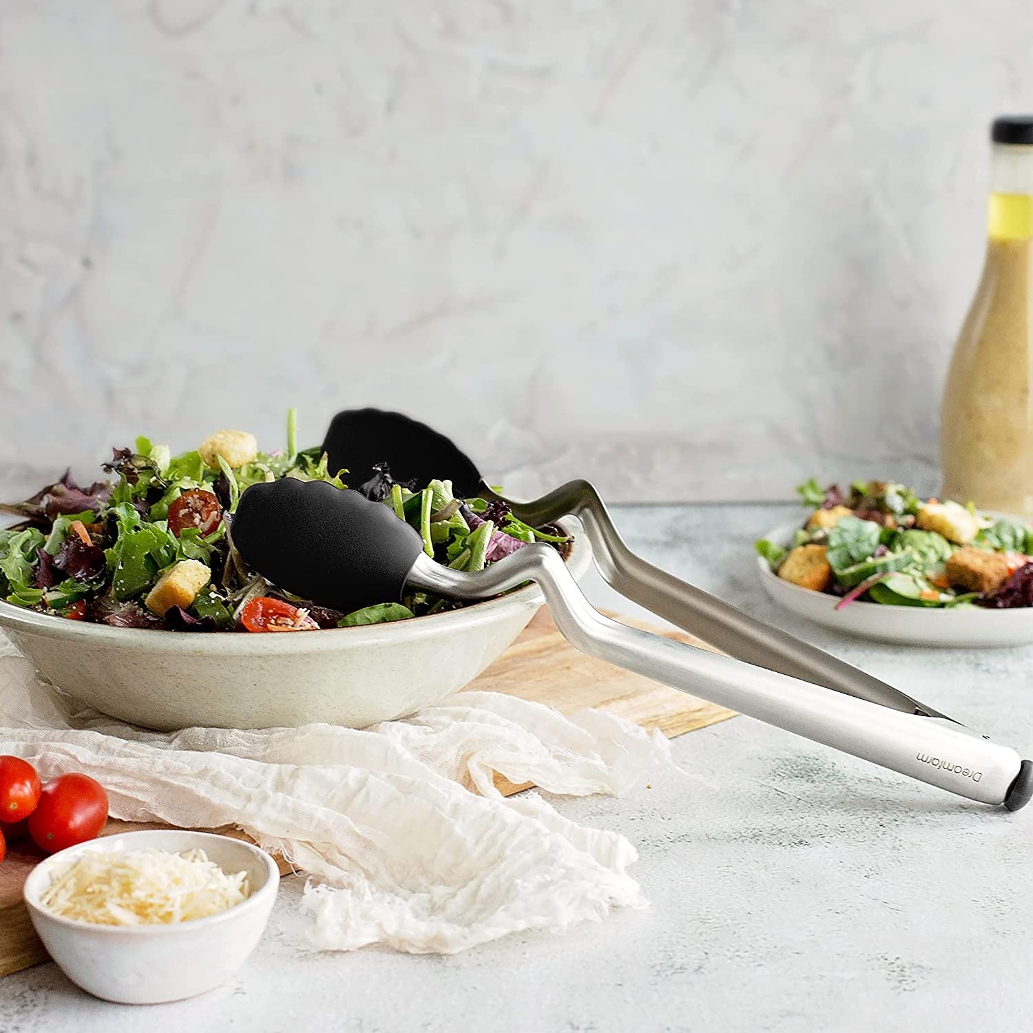 the tongs resting on a salad bowl