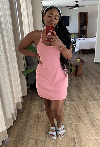 a reviewer wearing the sleeveless dress in pink 