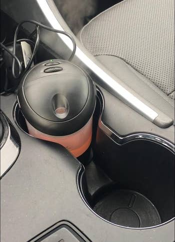 a reviewer photo of the diffuser in a car cup holder 