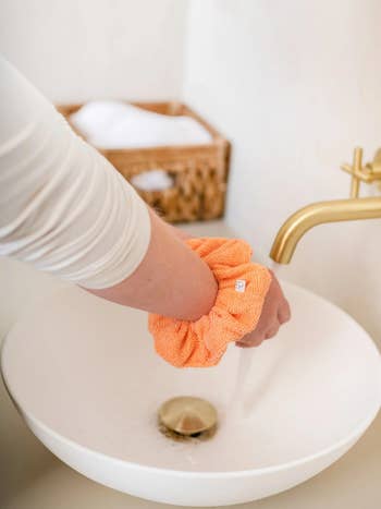 model with the peach scrunchie on their wrist while washing their hands