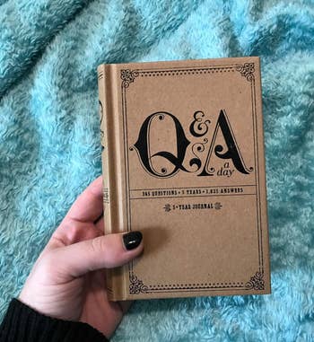 Person holding a 'Q&A a day' 5-year journal with their left hand