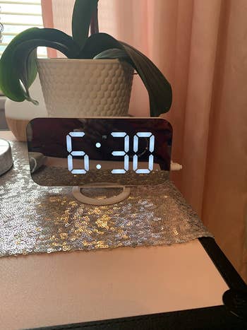 a mirrored digital alarm clock plugged in