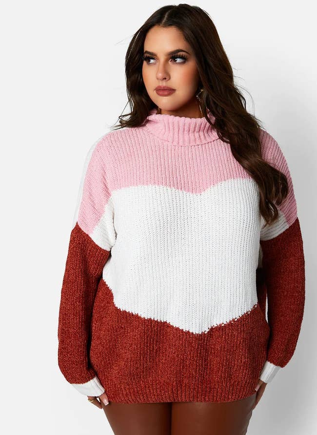 a model posing in the pink, red, and white sweater