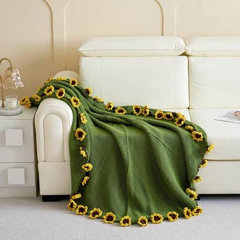 Knit broad  draped implicit    a sofa, featuring sunflower accents, displayed successful  a surviving  country   setting. Ideal for location  decor and comfort