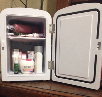 reviewer photo of an open mini fridge full of beauty products 
