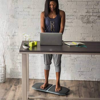 model using the balance board while standing at a desk