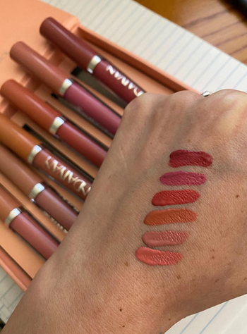 another reviewer wearing all six shades of matte pink and red from set B on their hand 