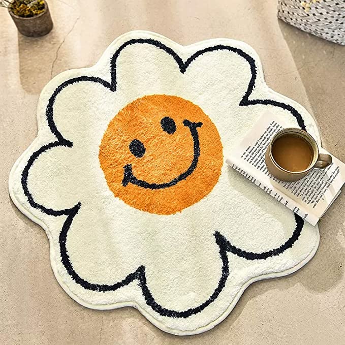 A rug with a yellow smiley face outlined with white petals 