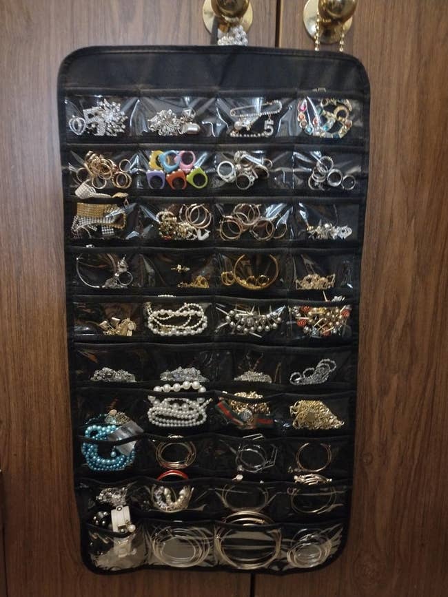 Hanging jewelry organizer filled with assorted earrings, necklaces, and bracelets, neatly displayed successful wide pockets
