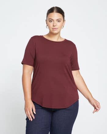 Person wearing a simple, short-sleeve apical  paired with jeans, posing confidently for a casual manner  showcase