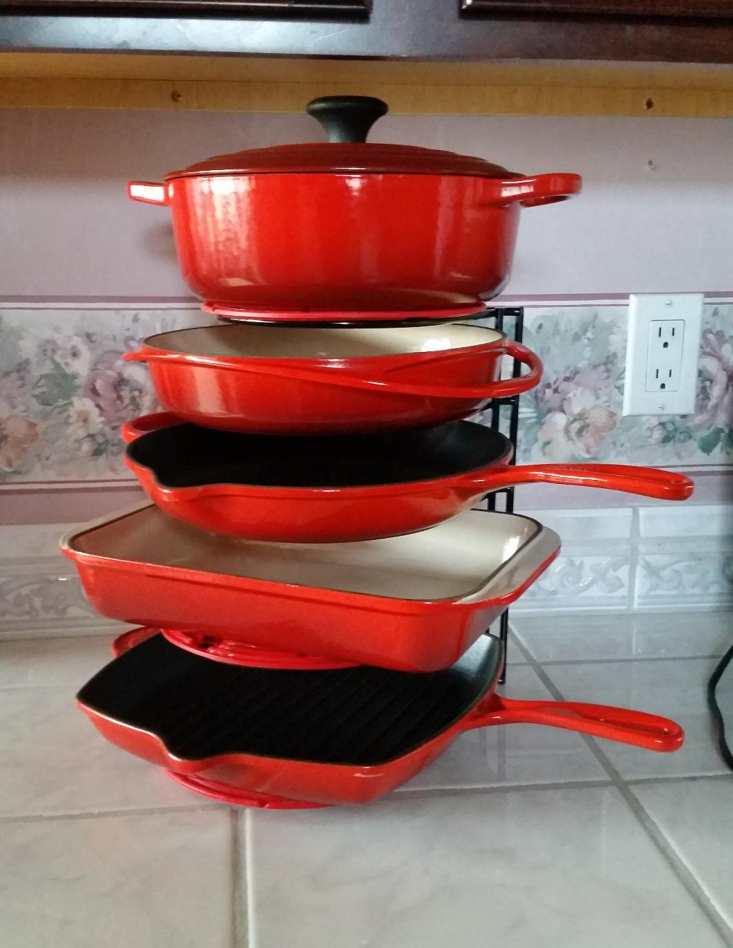 five pieces of red Le Creuset cast iron on this vertical organizer