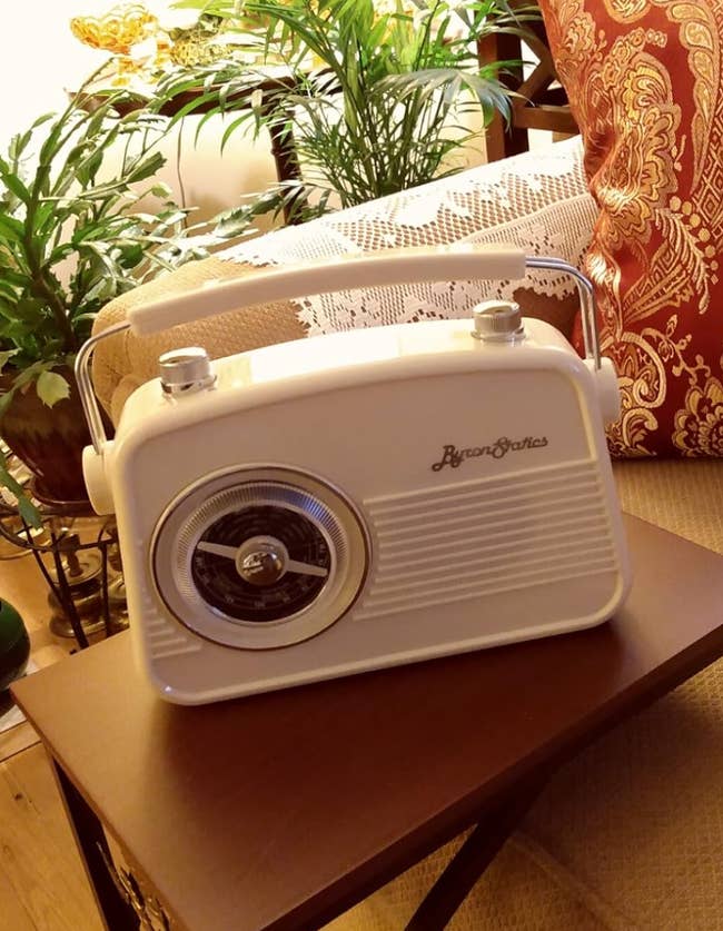 Vintage-style ByronStatics radio on a side table with plants and a couch in the background