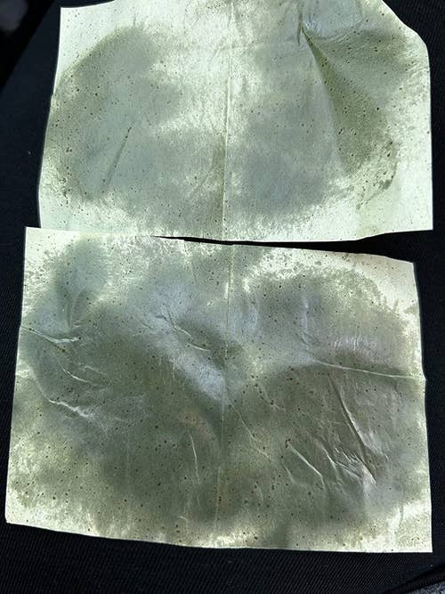 reviewer photo of two used blotting sheets that are covered in absorbed oil