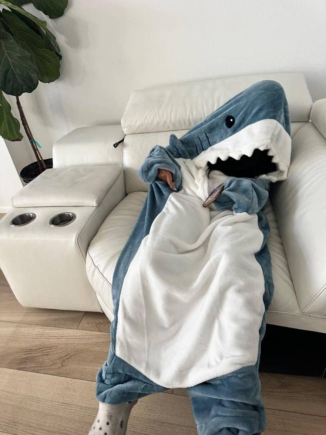 Person relaxing connected a sofa successful a cozy shark-themed broad with an unfastened rima design, creating a playful look