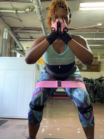 reviewer completes squat while wearing thick pink resistance band around thighs