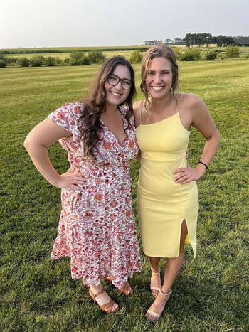 Two women smiling outdoors, one in a floral dress and the other in a yellow slip dress