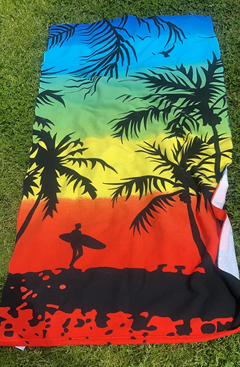 Reviewer image of multi-colored beach towel with palm trees and a surfer