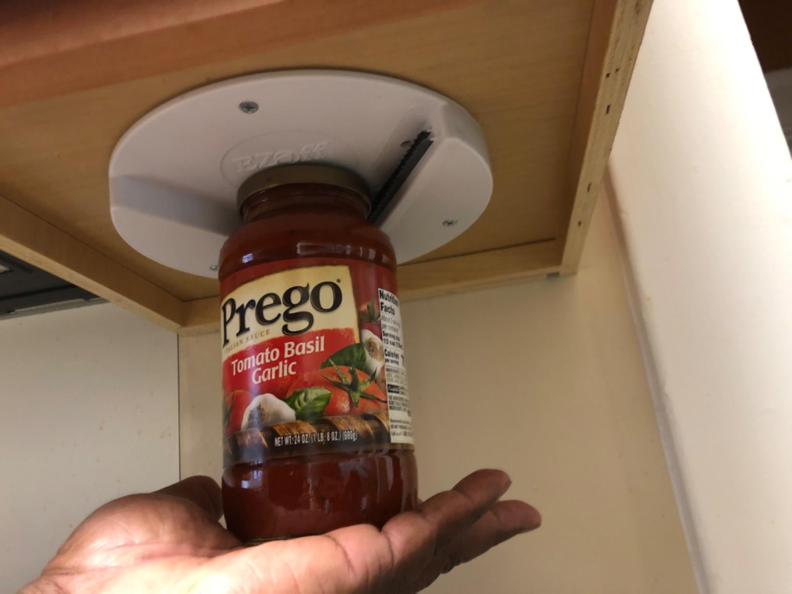 reviewer's hand using the opener attached to the bottom of a cabinet