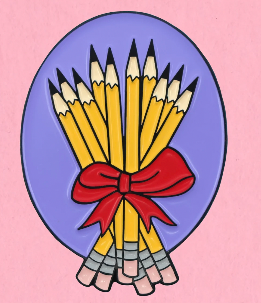 A purple enamel pin featuring a bouquet of pencils tied with red ribbon