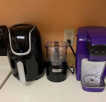 The chopper on a reviewer's counter next to an air fryer and coffee machine to show how small it is