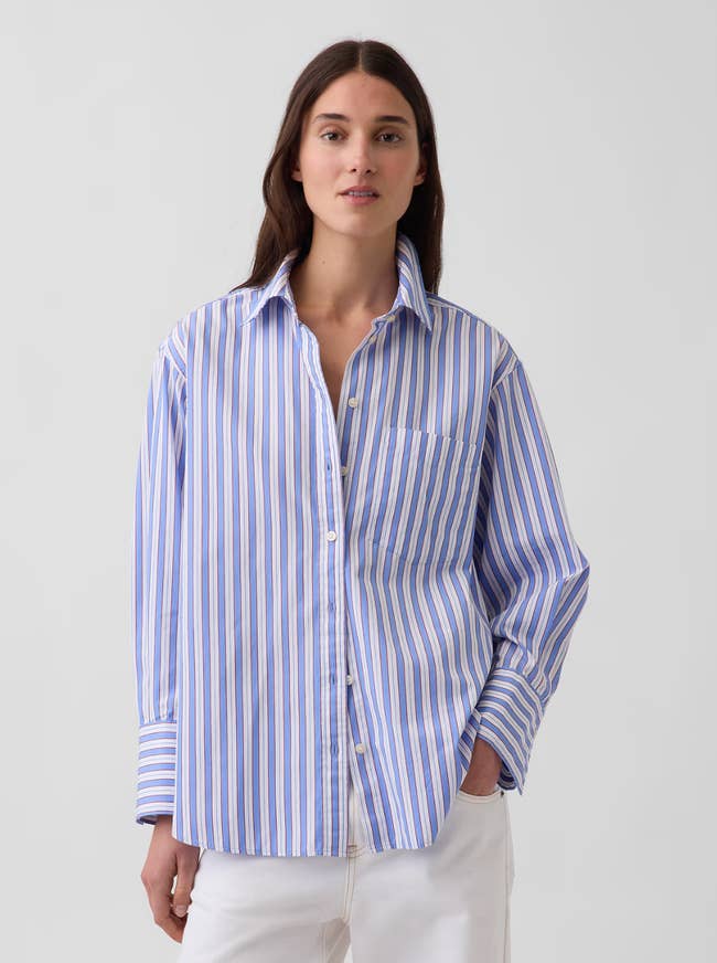 Person wearing an oversized striped button-up garment  with 1  manus  successful  pocket, lasting  against a plain background
